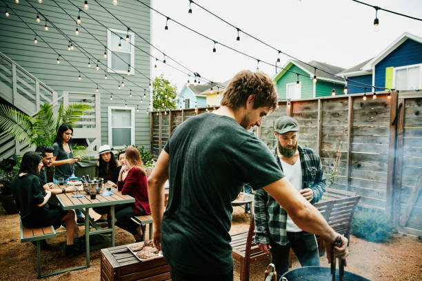 men grilling food for friends during backyard barbecue - garden decoration photos et images de collection