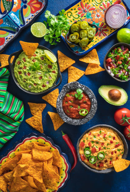 mexican dip sauces guacamole, cheedar dip, tomato salsa and pico de gallo with nacho chips - food stock pictures, royalty-free photos & images