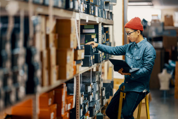 mid adult male retail shop staff checking or looking for inventory in a storage room - home decoration stock pictures, royalty-free photos & images