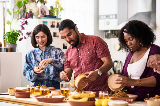 mid adult man and two female friends serving takeaway food at home - junk food stock pictures, royalty-free photos & images