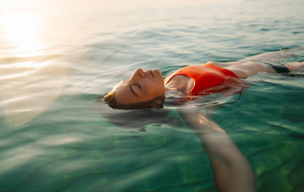 mid adult woman swimming in the calm sea water - travel stock pictures, royalty-free photos & images