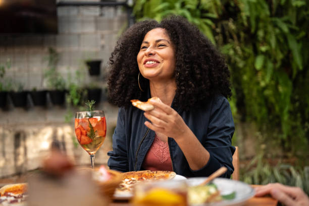 mid adult woman talking and eating with friends at restaurant - food stockfoto's en -beelden