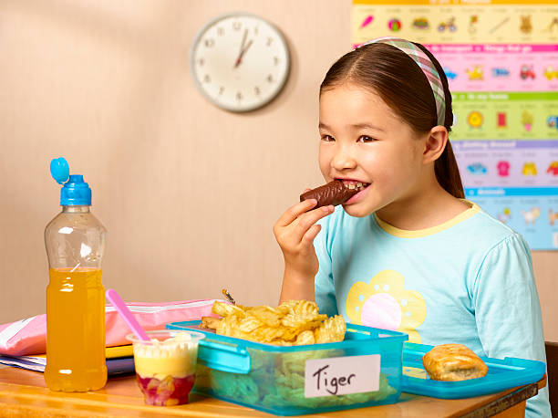 mixed race school girl eating junk food - junk food stockfoto's en -beelden