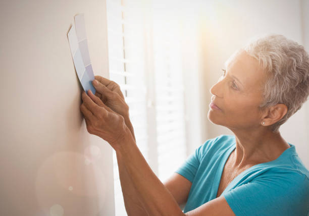mixed race woman choosing paint swatch - home decoration stock pictures, royalty-free photos & images