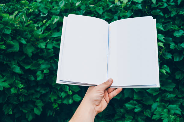 mock up of the book in hand man, against the background of green leaves. concept on the topic of education - back to school. - fashion stock pictures, royalty-free photos & images