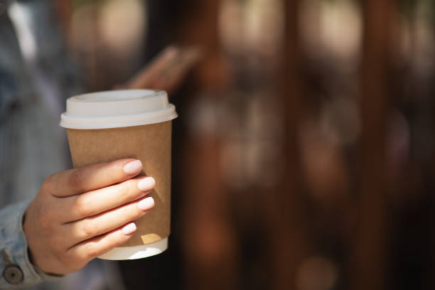 mockup of male hand holding a coffee paper cup isolated on light grey background. - junk food stock pictures, royalty-free photos & images