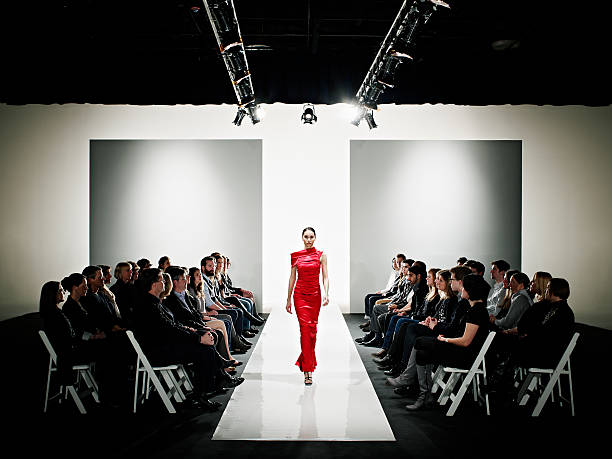 model in gown walking down catwalk at fashion show - fashion week stock pictures, royalty-free photos & images