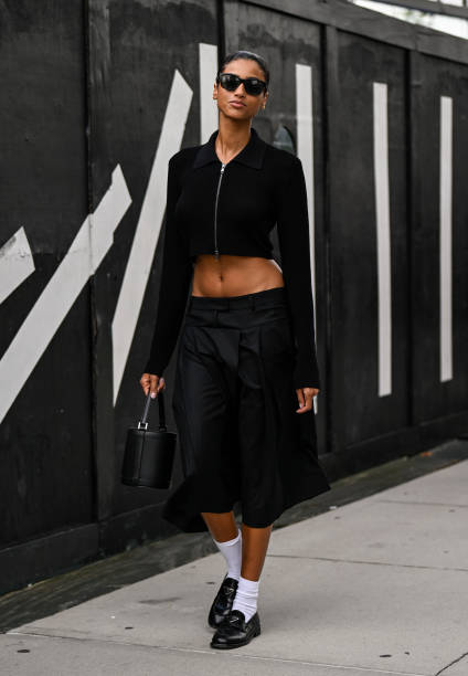 Model is seen wearing a black cropped jacket, black skirt, black bag, black shoes and black sungalsses outside the Michael Kors show during NYFW S/S...