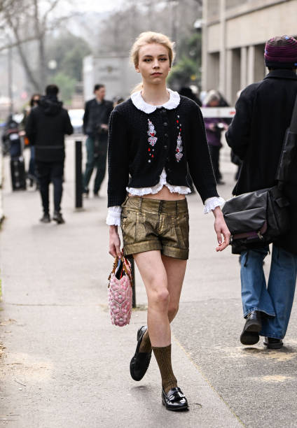 Model is seen wearing a black embellished cardigan, brown shorts, black shoes and pink bag outside the Miu Miu show during the Womenswear Fall/Winter...