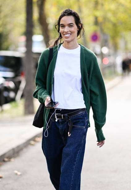 Model is seen wearing a green cardigan, white t-shirt and blue jeans with black bag outside the Miu Miu show during the Womenswear Spring/Summer 2024...