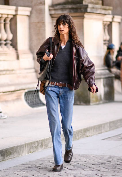 Model Mica Arganaraz is seen wearing a brown leather jacket, black sweater, blue jeans, brown belt and black bag outside the Louis Vuitton show...