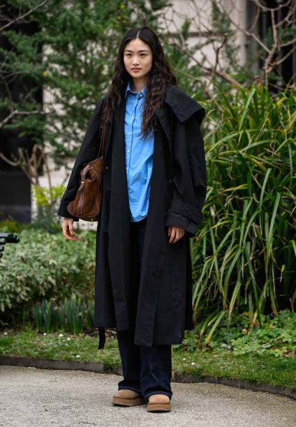 Model Xu Wei is seen wearing a black trench coat, blue shirt, black pants and tan shoes and brown bag outside the Zimmermann show during the...