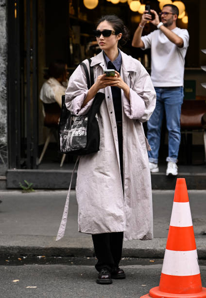 Model Xu Wei is seen wearing a tan trench coat, black bag and black Miu Miu sunglasses outside the Lacoste show during Womenswear Spring/Summer 2025...