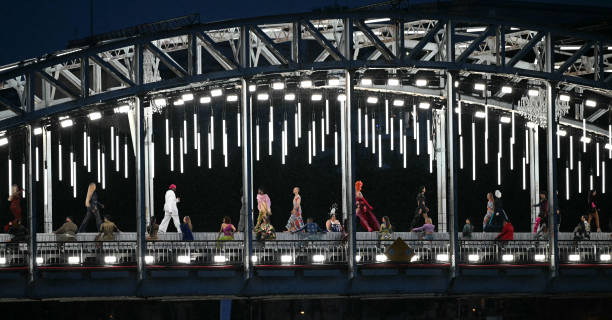 Models present creations while walking a catwalk erected along the Passerelle Debilly bridge along the Seine river during the opening ceremony of the...