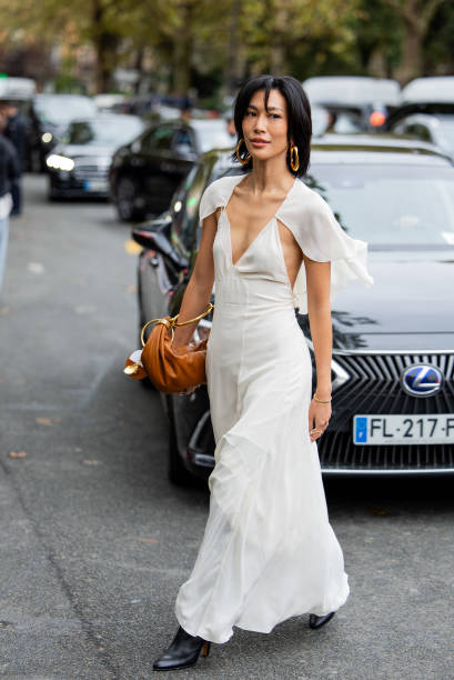 Molly Chiang wears white cut out dress, brown bag, black over knees boots outside Chloe during Womenswear Spring/Summer 2025 as part of Paris Fashion...