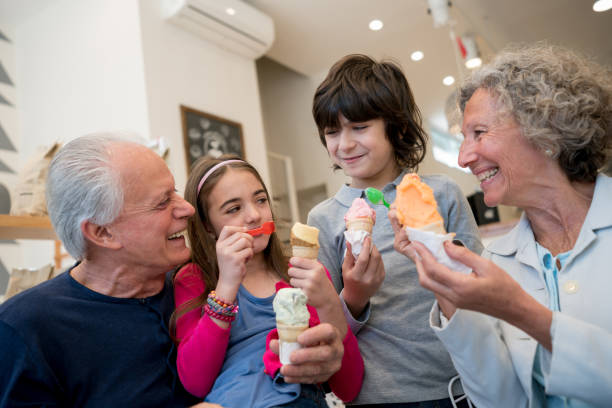 mooie grootouders delen van tijd met hun kleinkinderen op het ijs salon - junk food stockfoto's en -beelden