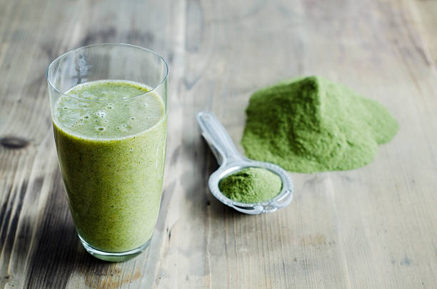 moringa powder on spoon and wooden table and glass of moringa smoothie - food fotografías e imágenes de stock