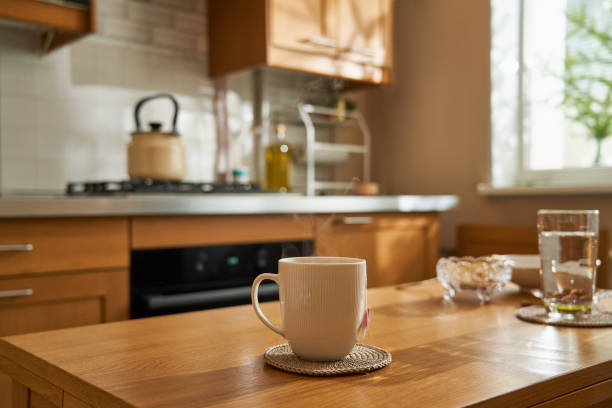 morning in home kitchen, hot tea in cup on wooden table, sunlight from window. - food stock pictures, royalty-free photos & images