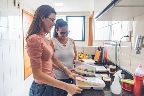 mother and adult daughter unpacking take-away food on the kitchen counter - junk food stock pictures, royalty-free photos & images