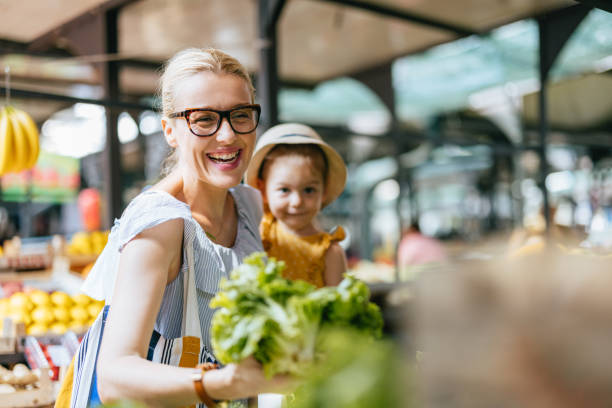 mother and daughter buying lettuce at the green market - food stock pictures, royalty-free photos & images