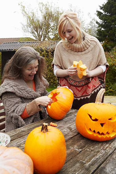 mother and daughter carving pumpkins - garden decoration stock pictures, royalty-free photos & images