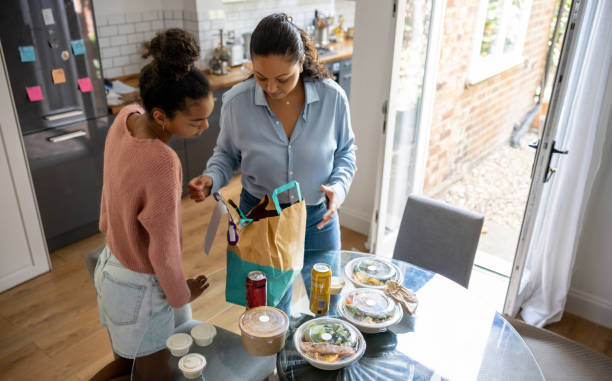 mother and daughter eating take out food at home - junk food stock pictures, royalty-free photos & images