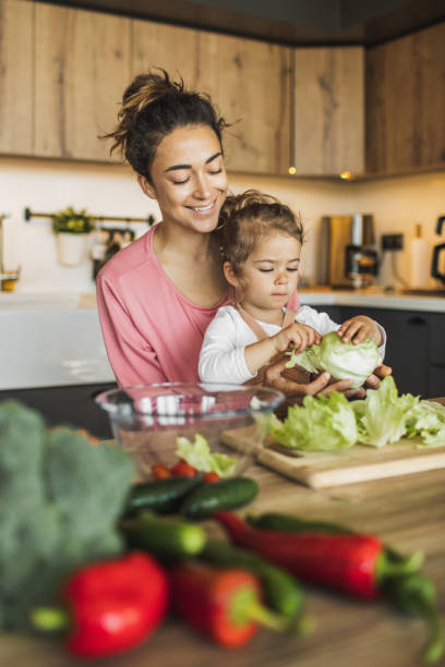 mother with daughter cooking together at kitchen. making fresh salad with greens and organic farm vegetables - food stock pictures, royalty-free photos & images