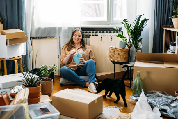 moving day: happy plus size woman sitting on the floor among boxes having a lunch break - junk food stock pictures, royalty-free photos & images
