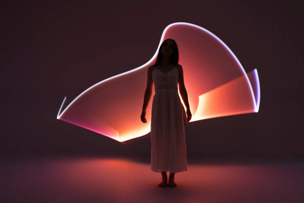 mujer joven frente a senderos de luz naranja. - fashion fotografías e imágenes de stock