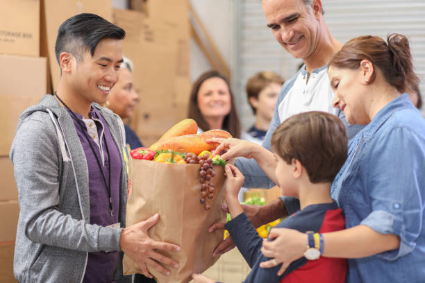 multi-ethnic group of volunteers work at food bank. - food stock pictures, royalty-free photos & images