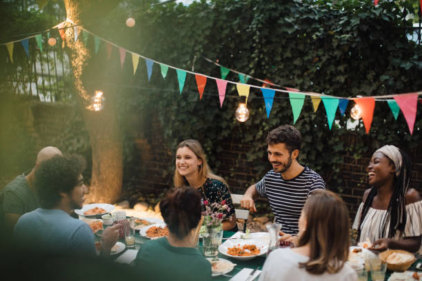 multi-ethnic young friends enjoying dinner at table during garden party - garden decoration stock pictures, royalty-free photos & images