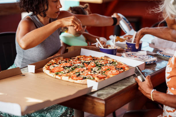 multi-generation family eats takeout pizza together - junk food stock pictures, royalty-free photos & images