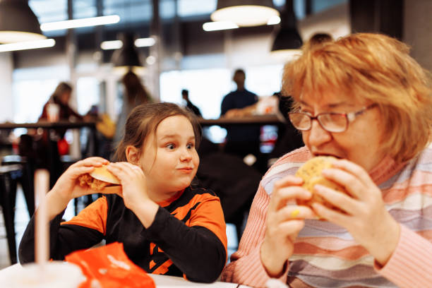 multigenerational family enjoying dinner at fast food restaurant - junk food stock pictures, royalty-free photos & images