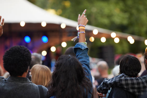 multiracial couple with arms raised enjoying concert - concert stock pictures, royalty-free photos & images