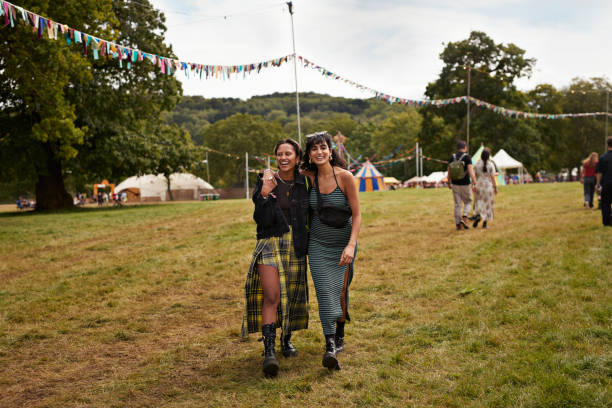 multiracial female friends walking with arms around - concert stock pictures, royalty-free photos & images