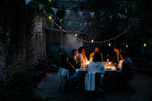 multiracial friends during dinner party in illuminated back yard - garden decoration stock pictures, royalty-free photos & images