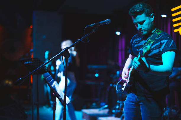 musicians playing electric guitar and singing on stage - concert stock pictures, royalty-free photos & images