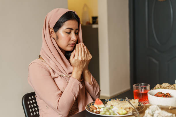 muslim woman reciting a prayer before iftar. - food fotografías e imágenes de stock