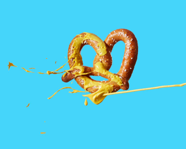 mustard squirting on pretzel - junk food stock pictures, royalty-free photos & images