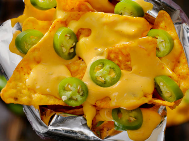 nacho tortilla chips in a bag with cheese sauce and jalapenos - junk food stock pictures, royalty-free photos & images