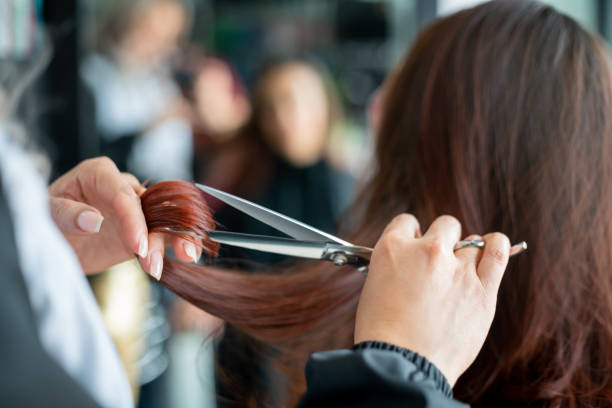 nahaufnahme eines nicht wiederzuerkennbaren friseurs, der einer kundin die haare schneidet - hairstyle stock-fotos und bilder