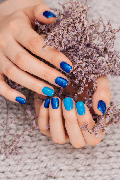 nails of women covered in blue lacquer different shades with rhinestones and with flowers in his hand. - nails art stock pictures, royalty-free photos & images