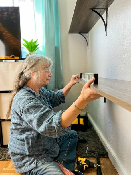 nette seniorin, die regale mit werkzeugen im schlafzimmer aufstellt. - home decoration stock-fotos und bilder