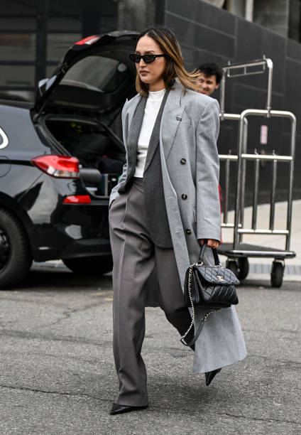 Nicole Warne is seen wearing a light gray coat, gray suit, white top and black sunglasses with black chain Chanelbag outside the Jason Wu show during...