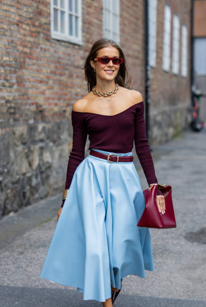 Nina Sandbech is seen wearing high waisted blue pleated skirt, burgundy off shoulder top, Gucci sunglasses, bag, necklace at Oslo Fashion Week on...