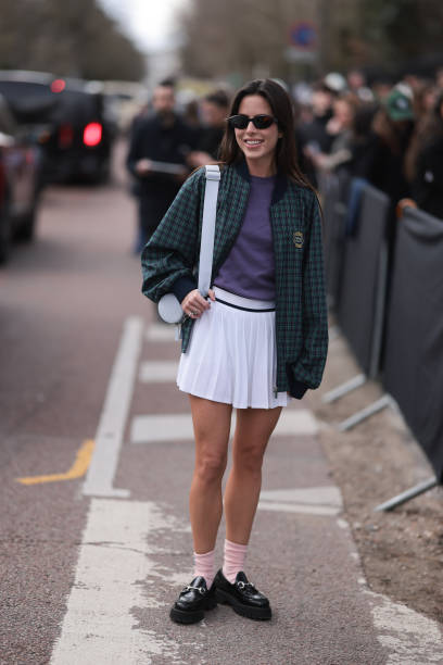Nina Urgell Cloquell seen wearing a white tennis skirt, green and black checkered Lacoste jacket, purple shirt, black shades, black leather loafer,...