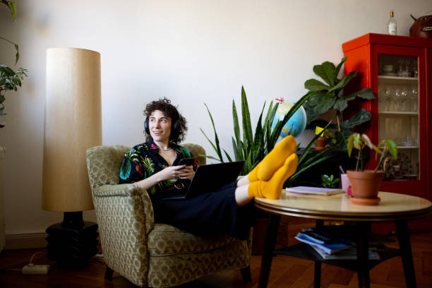 non-binary person listening to music while working on laptop at home - fashion photos et images de collection