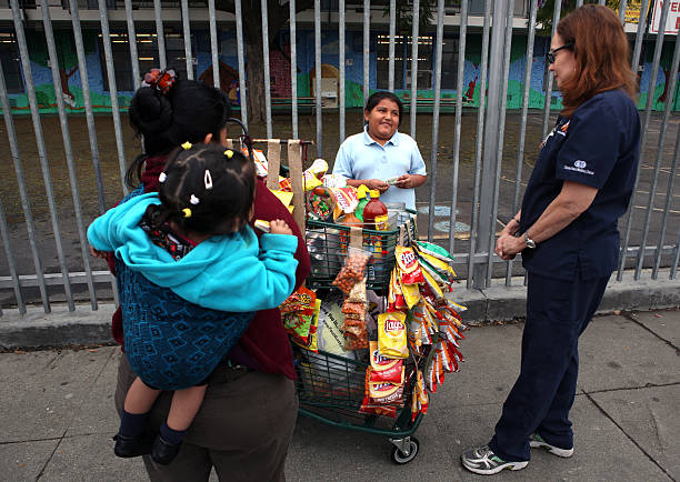 Nurse practitioner Anne Traynor, right, talks to 8-year-old Dafne Sanchez, center, who wanted to buy junk food from a vendor, at left, after she got...