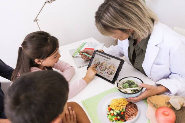 nutritionist and little patients with their mother during a medical consultation in the doctor's office - food stock pictures, royalty-free photos & images