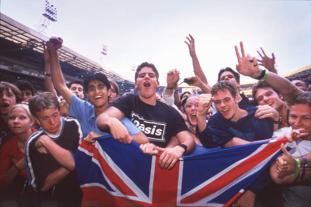 Oasis fans holding a union jack flag in the audience at Wembley Stadium, London, 21st July 2000.
